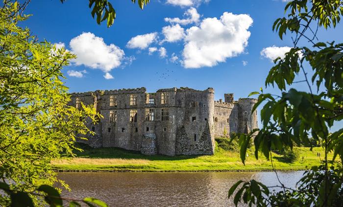 View of Carew Castle through some trees showing some pond